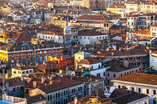 Aerial view of Venice, Italy, at sunset with rooftops of buildings and warm sunlight.