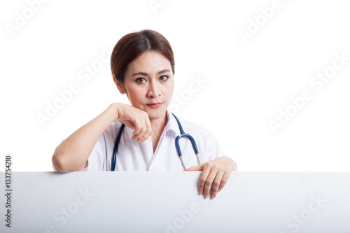 Young Asian female doctor standing behind blank white billboard.