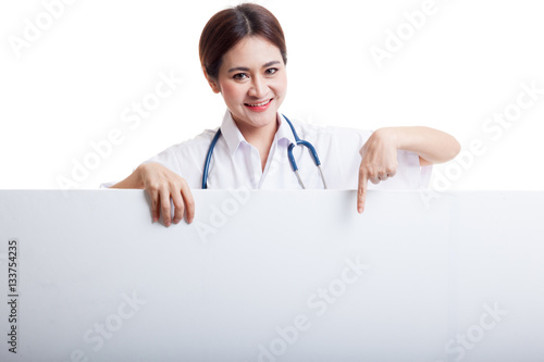 Young Asian female doctor point down to blank sign.