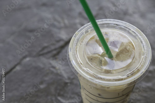 ice coffee in plastic glass with green straw on granite background  .