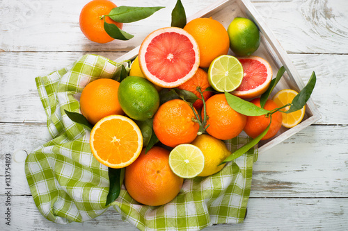 Citrus fruit in wooden tray on white table. Healthy eating and diet. © nadianb