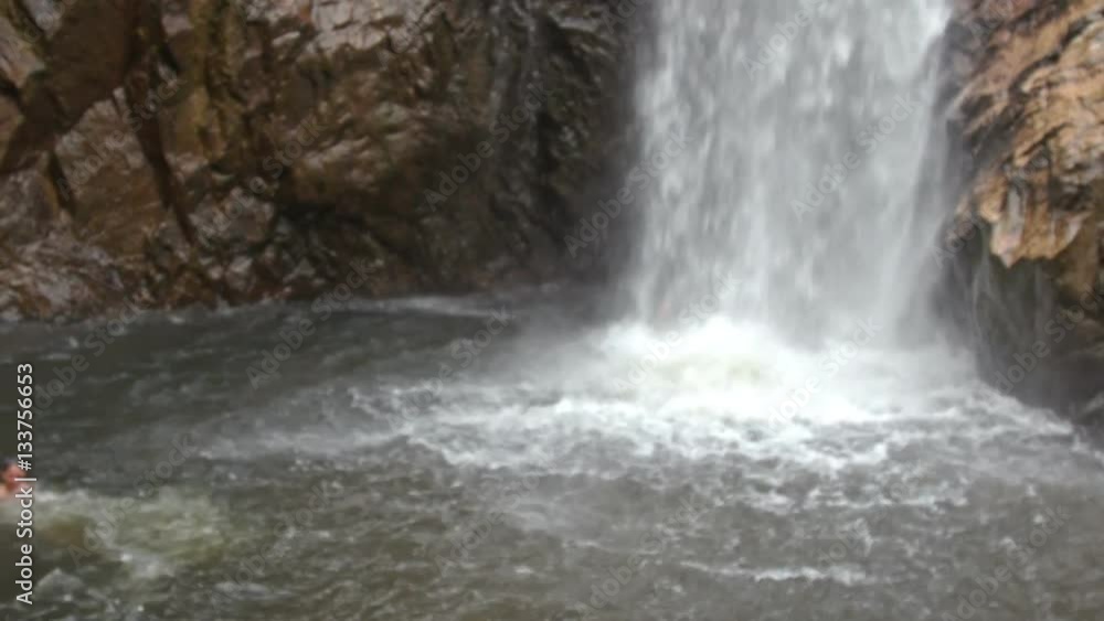 Guy Swims up to High Waterfall Foamy Splashes among Rocks Guy Swims up to High Waterfall Foamy Splashes among Rocks