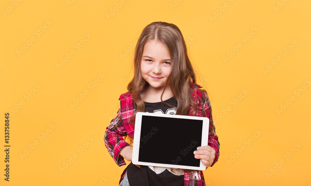 little girl showing blank black tablet pc on yellow background little girl showing blank black tablet pc on yellow background