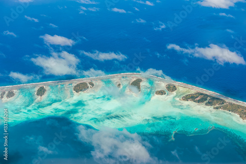 Aerial view of the island with clouds, reef and lagoon. Island n