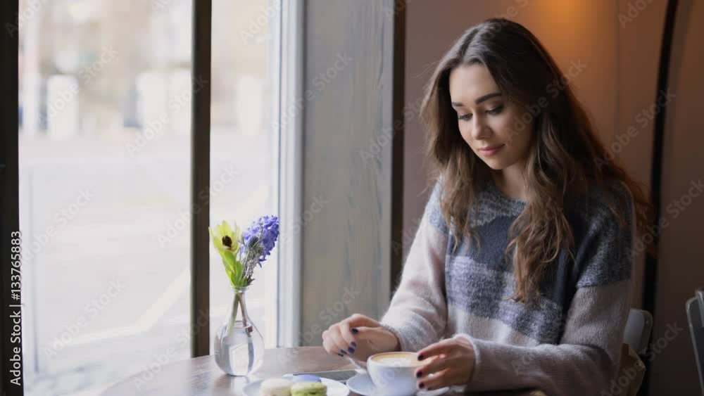 Beautiful young woman looking at the window and drinking coffee in cafe Beautiful young woman looking at the window and drinking coffee in cafe