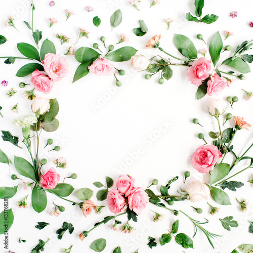 Round frame made of pink and beige roses, green leaves, branches, floral pattern on white background. Flat lay, top view. Valentine's background