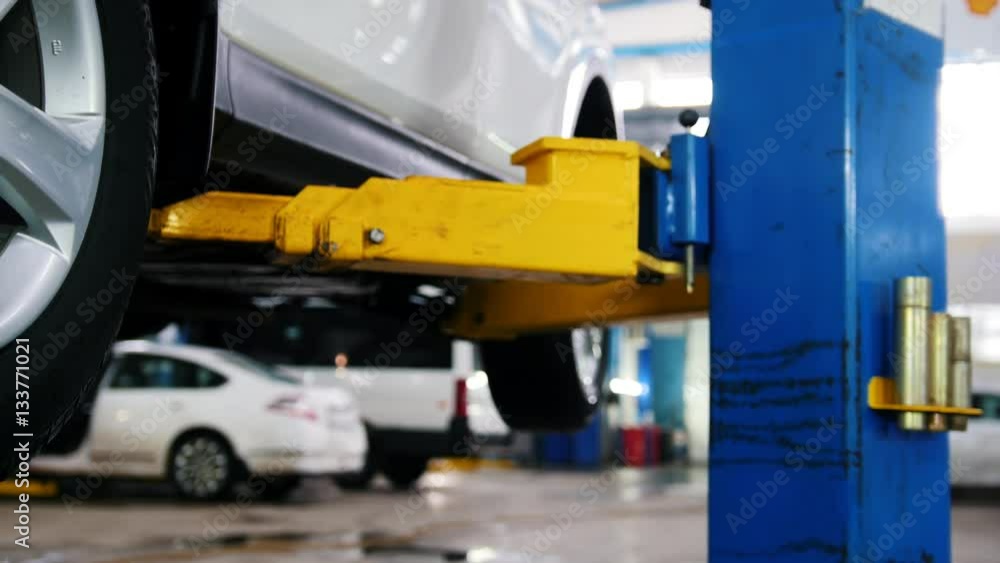 Car in auto service lifting for repairing, mechanics in garage