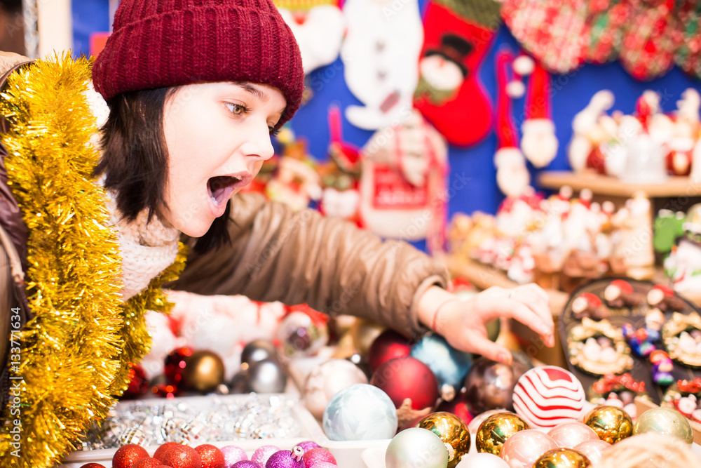 girl choosing Christmas decoration at market