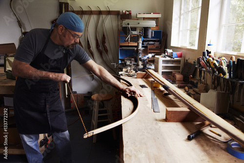 A bowman, a skilled man making a bow, in his workshop. 