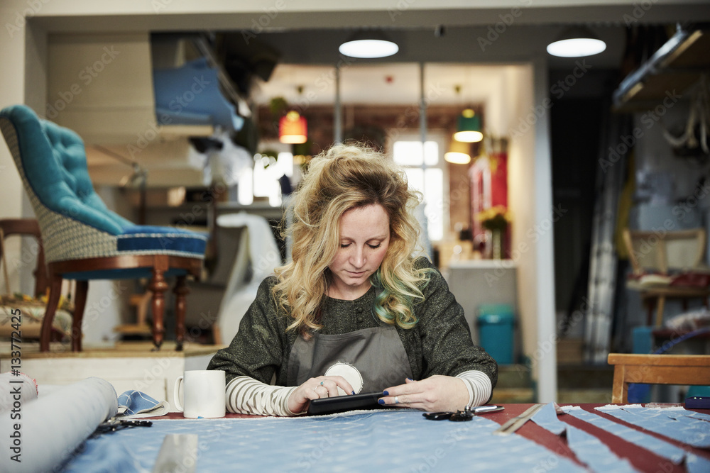 A woman preparing, measuring and cutting upholstery fabric on a workbench. A woman preparing, measuring and cutting upholstery fabric on a workbench.