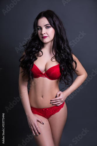 sexy beautiful plus size model in red lingerie over black backgr