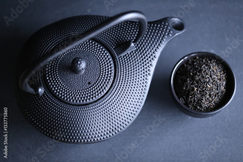 Black teapot in oriental style and cup of tea leaves on black background. 1