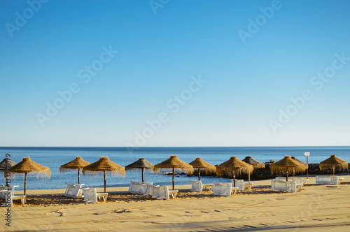 Holiday and vocation image with beach lounge and parasol on ocean sea outdoors sunny background