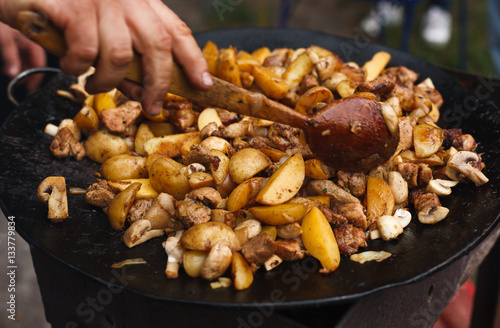 Roasted potatoes with meat cooked in metal cauldron pot