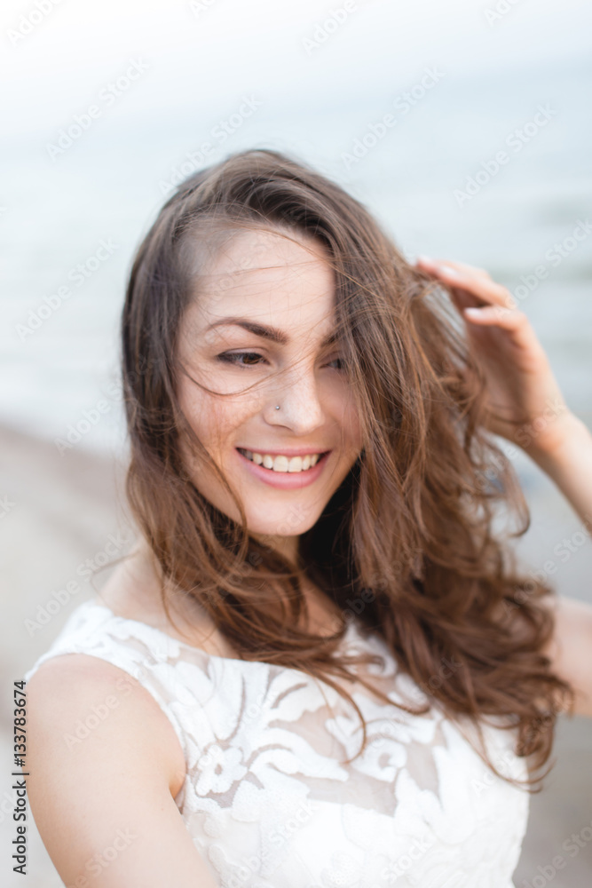 Beautiful young brunette woman in white long dress at the sea shore Beautiful young brunette woman in white long dress at the sea shore