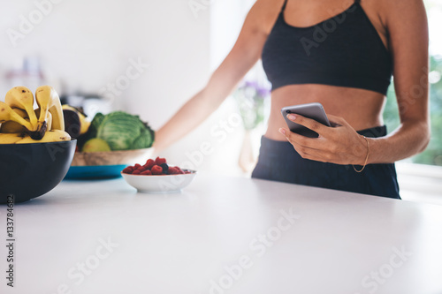 Young woman with mobile phone in kitchen