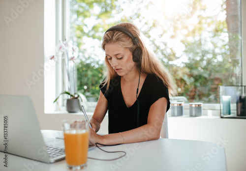 Serious young woman studying in kitchen