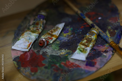 Oil paints and paint brushes on a palette close up.