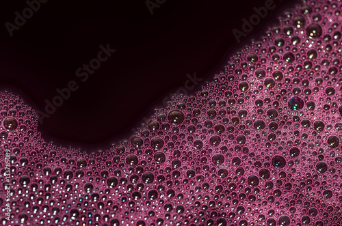 Bubbles of red wine closeup. Alcoholic background