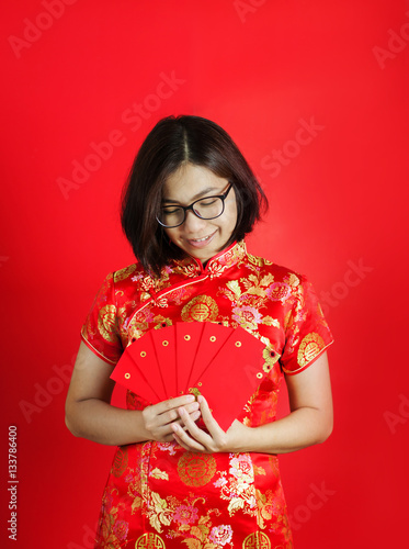 Asian glasses woman with cheongsam holding red envelopes . © eggeeggjiew