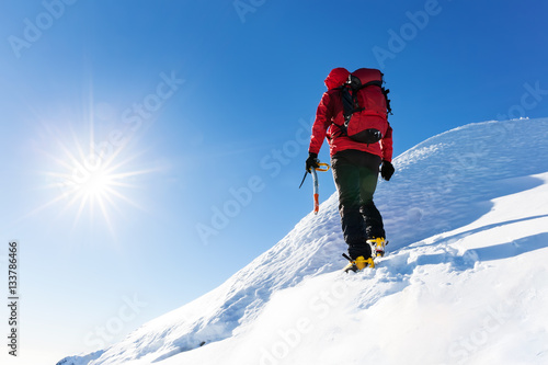 Extreme winter sports: climber reachs the top of a snowy peak in the Alps. Concepts: determination, success, brave.