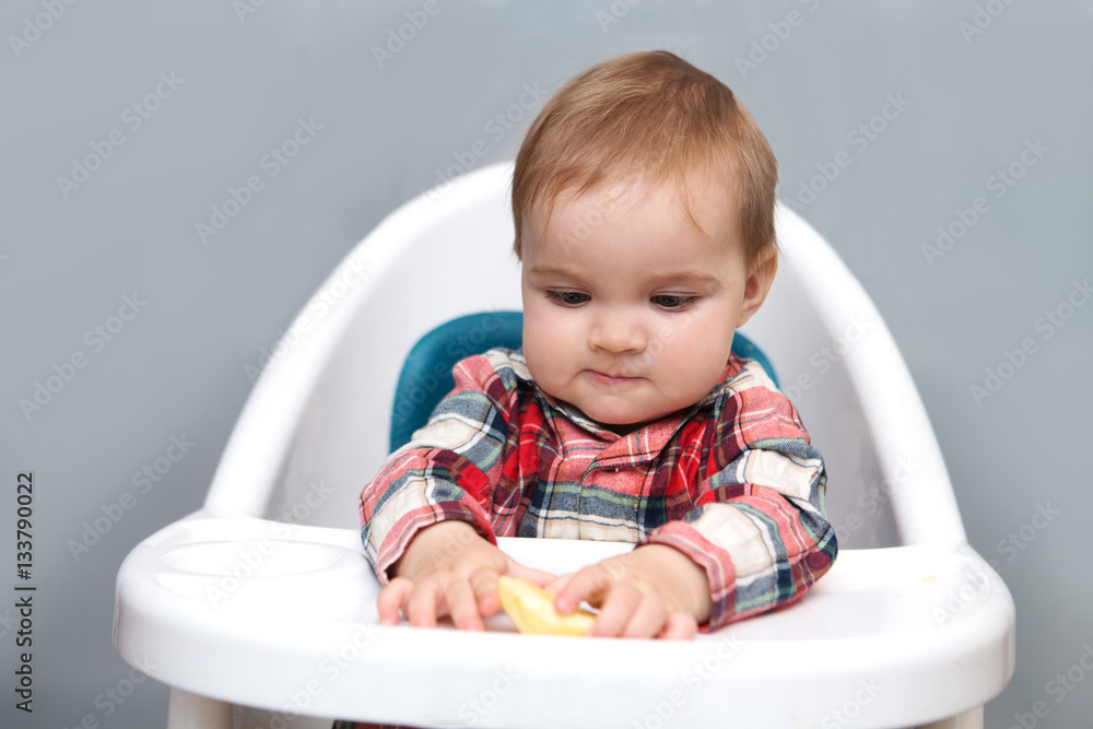 Smiling baby eating apple In High Chair. Baby eating healthy foods. Smiling baby eating apple In High Chair. Baby eating healthy foods.