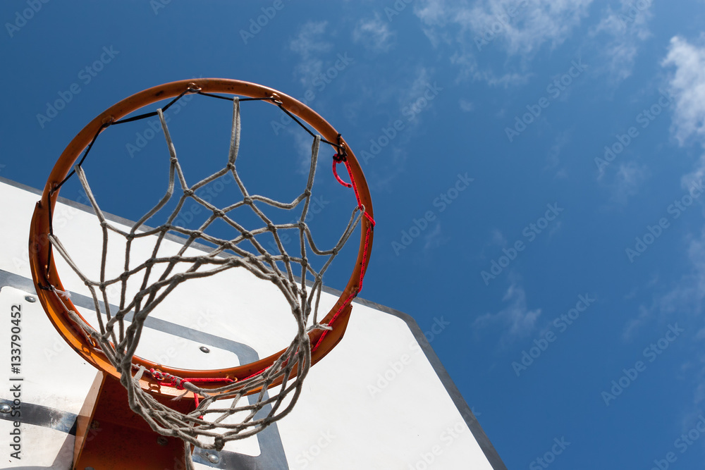 worn but repaired basketball hoop net against the blue sky.