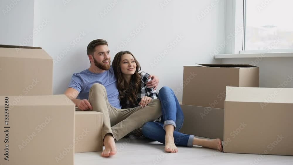 Young happy couple sitting on the floor of their new appartment and planning redecoration Young happy couple sitting on the floor of their new appartment and planning redecoration