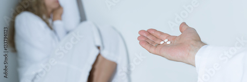 Doctor giving pills to frightened woman