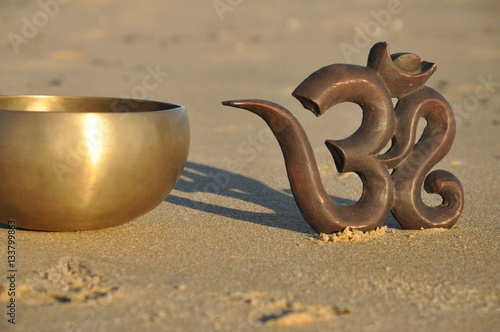 Om symbol with singing bowl on beach