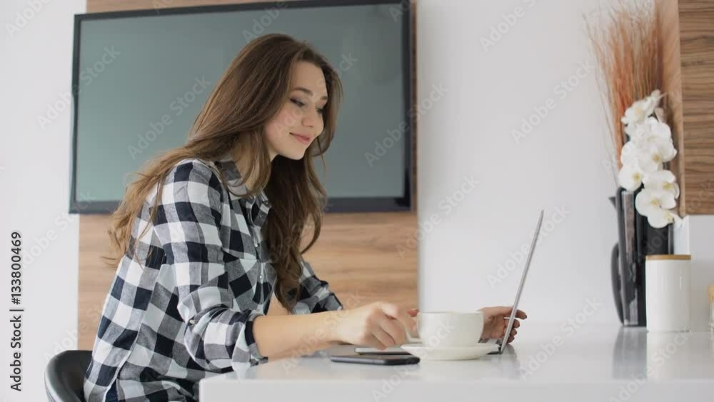 Young lovely woman drinking coffee while using laptop at home Young lovely woman drinking coffee while using laptop at home