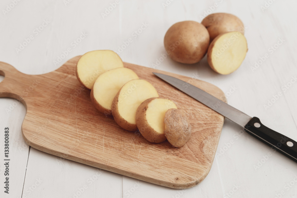 Sliced potatoes on a wooden board rustic style with knife Sliced potatoes on a wooden board rustic style with knife