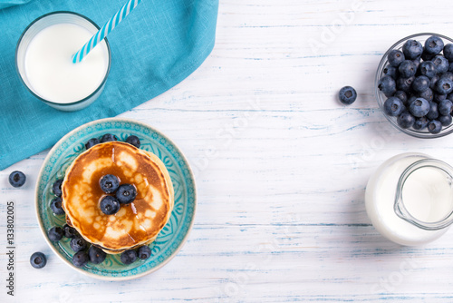 Stack of pancakes with fresh blueberry, honey and milk, healthy breakfast concept, top view