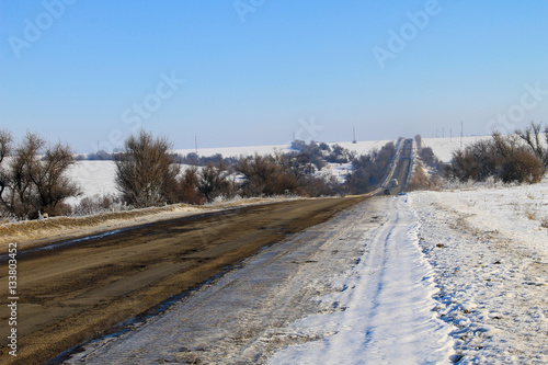 Broken cracked asphalt road on winter © olyasolodenko