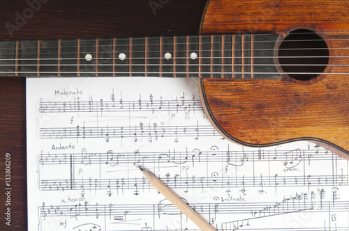 Music notes, vintage guitar and two pencils on table