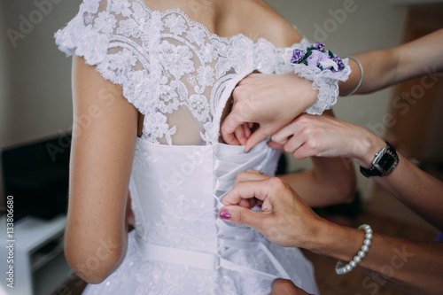 bridesmaid tying bow on wedding dress © dashamuller