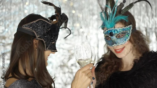 Women in carnival masks having a toast and smiling to the camera, steadycam shot
