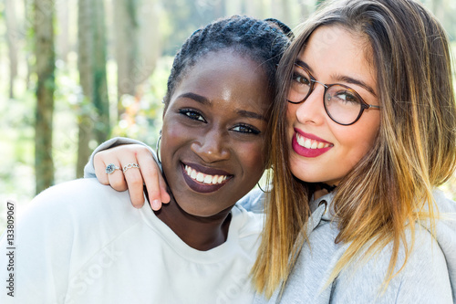 Diverse portrait of two attractive teen girlfriends outdoors.Face shot of black girl with white friend. photo