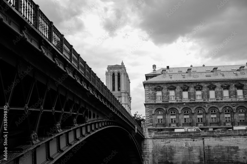 Bridge over the Seine river, tower of the Notre Dame cathedral in Paris, black and white 