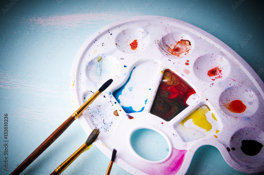 art palette with paint and brushes, close up art palette with paint and brushes, close up