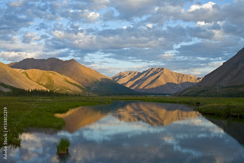 Mountains in sunset light and reflections in the lake. Ridge Cherskogo. Yakutia. Russia. Mountains in sunset light and reflections in the lake. Ridge Cherskogo. Yakutia. Russia.