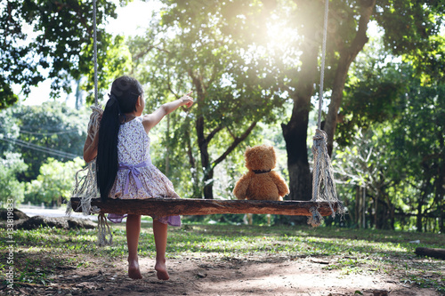 girl sitting on a swing with Teddy bear
