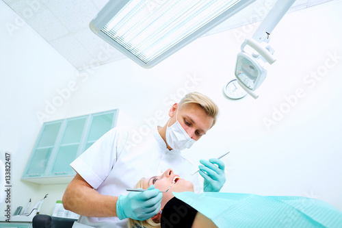 The dentist treats a patient  mask in  dental office.