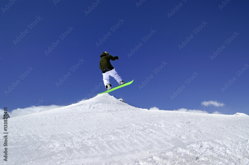 Snowboarder jump in snow park at ski resort on sun winter day