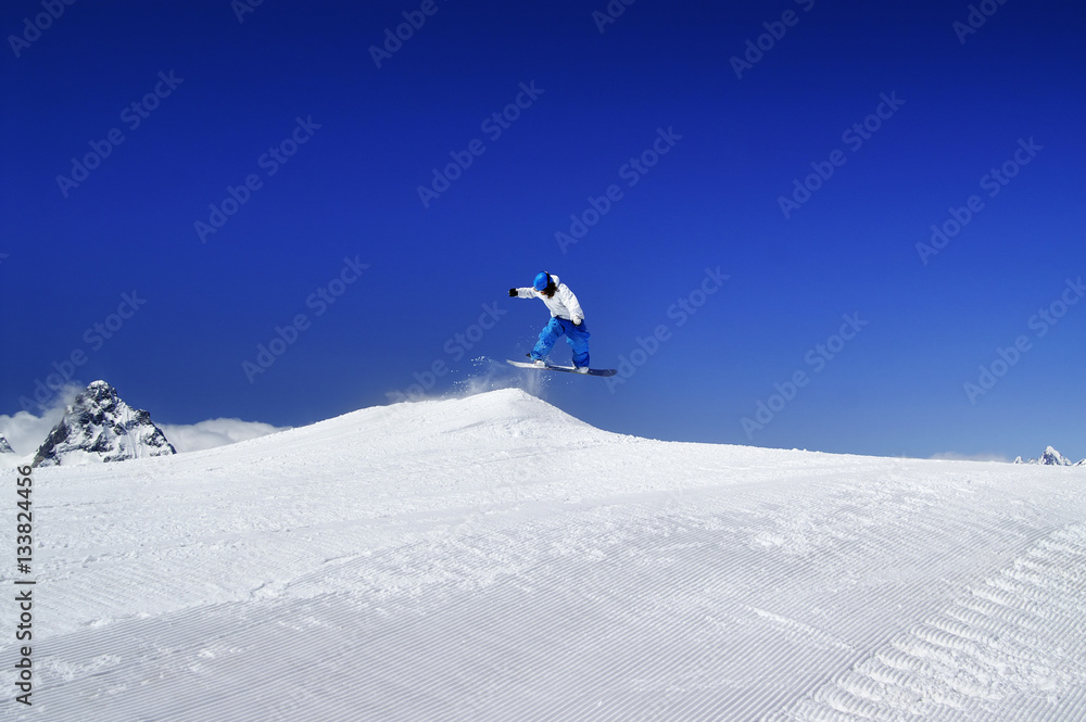 Snowboarder jump in snow park at ski resort on sunny winter day