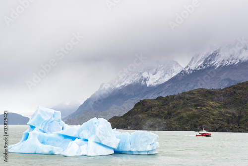 Floating iceberg and a small boat in Grey glacier lake, Torres del Paine National Park, Patagonia, Chile