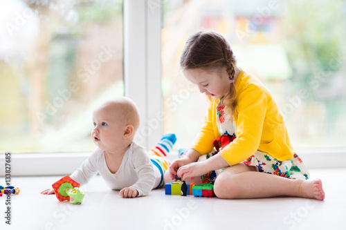 Sister and baby brother play with toy blocks