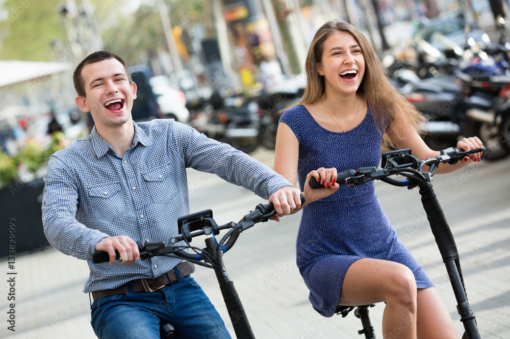Obraz premium Happy young man and woman with electrkc bikes