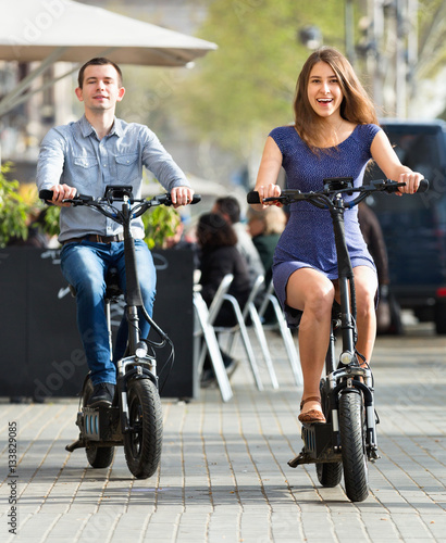 Happy young man and woman with electrkc bikes photo