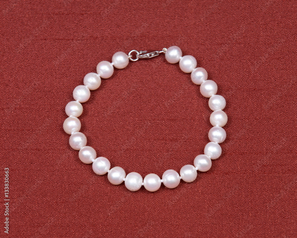 Freshwater white pearl necklace on red fabric background Freshwater white pearl necklace on red fabric background